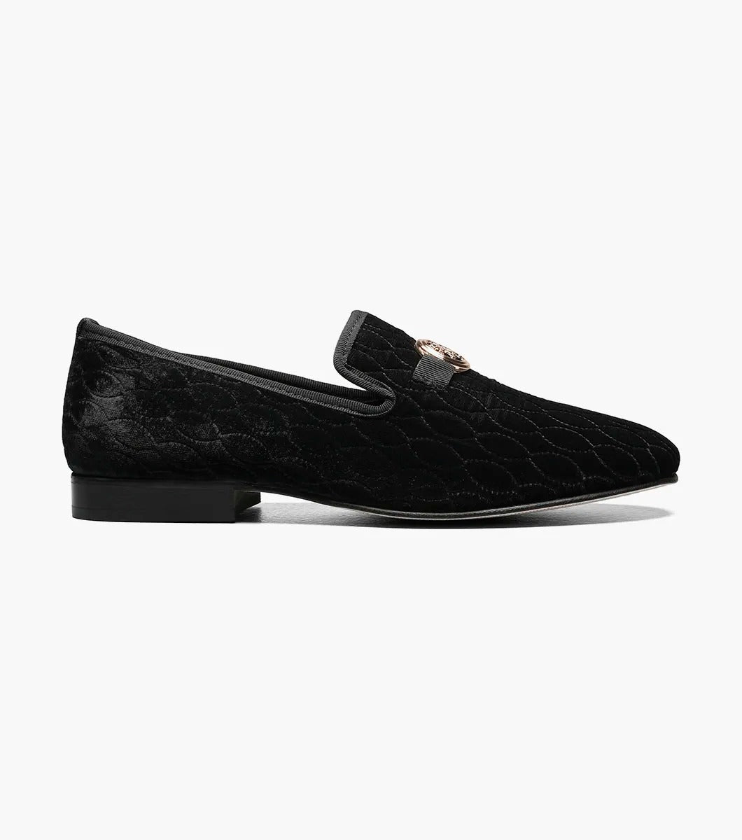 The Stacy Adams VALET Slip On Bit Loafer in Black (25166-001) showcases a black velvet design with a quilted pattern and gold emblem on top, enhanced by a genuine leather sole and cushioned with a Memory Foam insole for superior comfort.