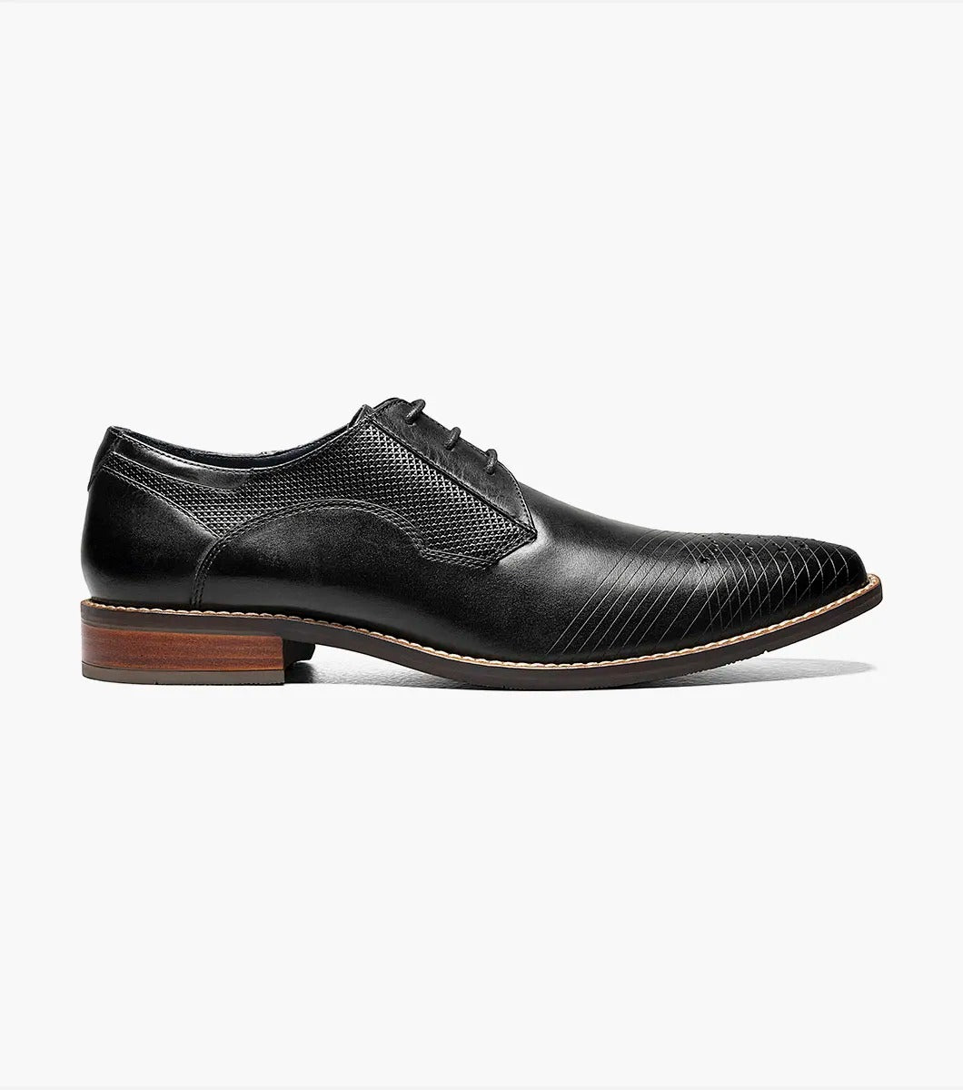 The Stacy Adams - JOVIAN Plain Toe Laser Oxford in black, product code 25504-001, is a premium dress shoe boasting a lace-up closure and distinctive brown detailing on the sole. Made from laser-treated leather for a sleek finish, it includes a Memory Foam insole to enhance comfort.