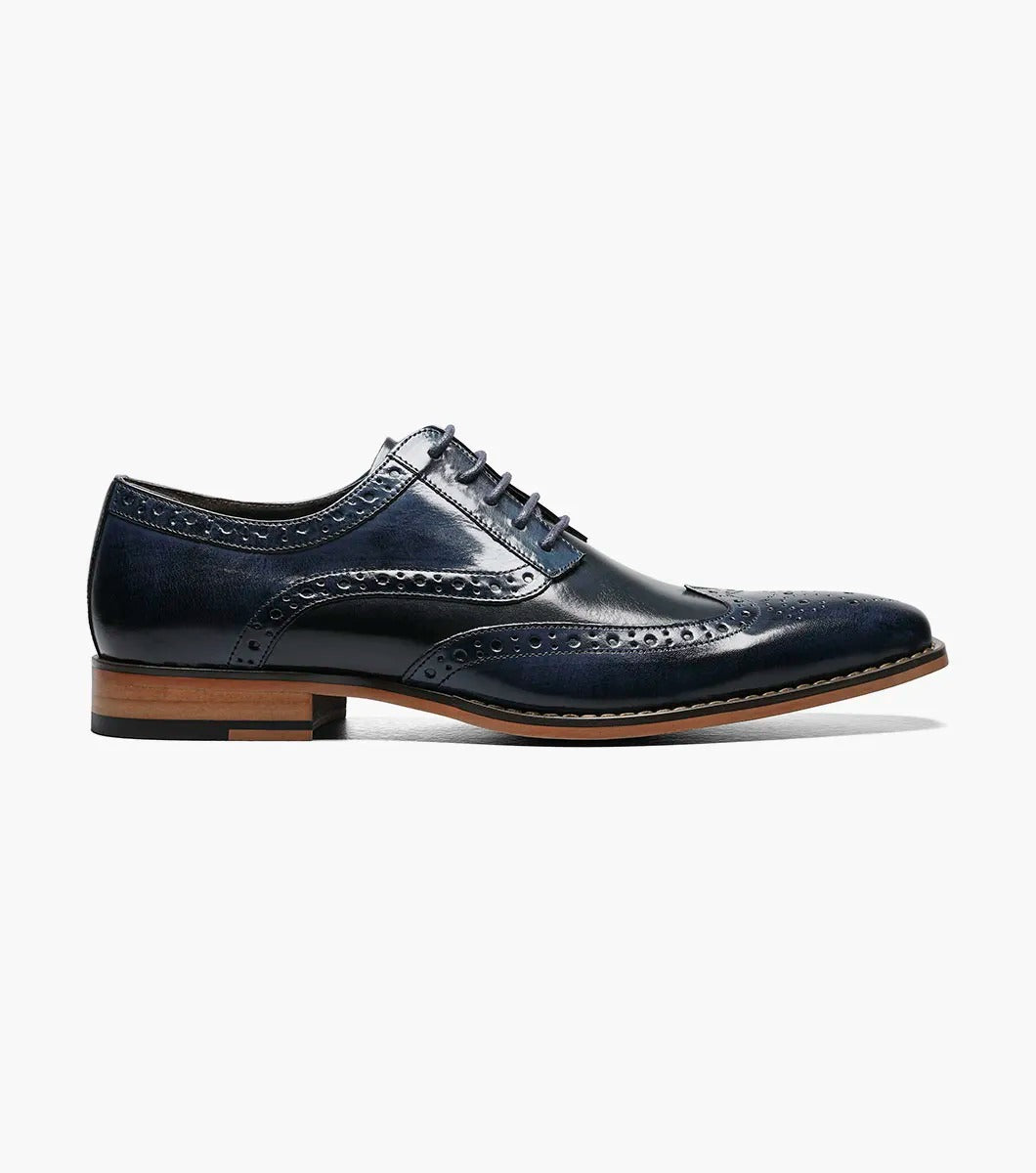 A Stacy Adams TINSLEY Wingtip Oxford in Cobalt Multi, featuring buffalo leather with decorative perforations, memory foam for added comfort, a wooden heel, and laces.