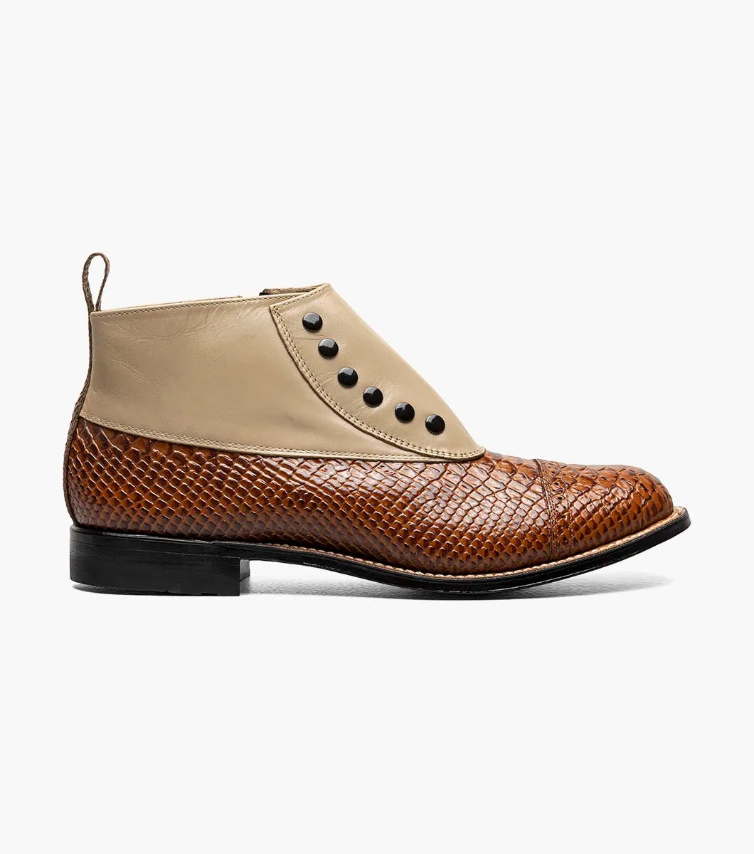 The Stacy Adams MADISON Spectator Spat Cap Toe Demi Boot in Tan Multi showcases a sophisticated design with a smooth kidskin leather upper, textured lower, and black side buttons, complemented by a genuine leather sole for timeless elegance.