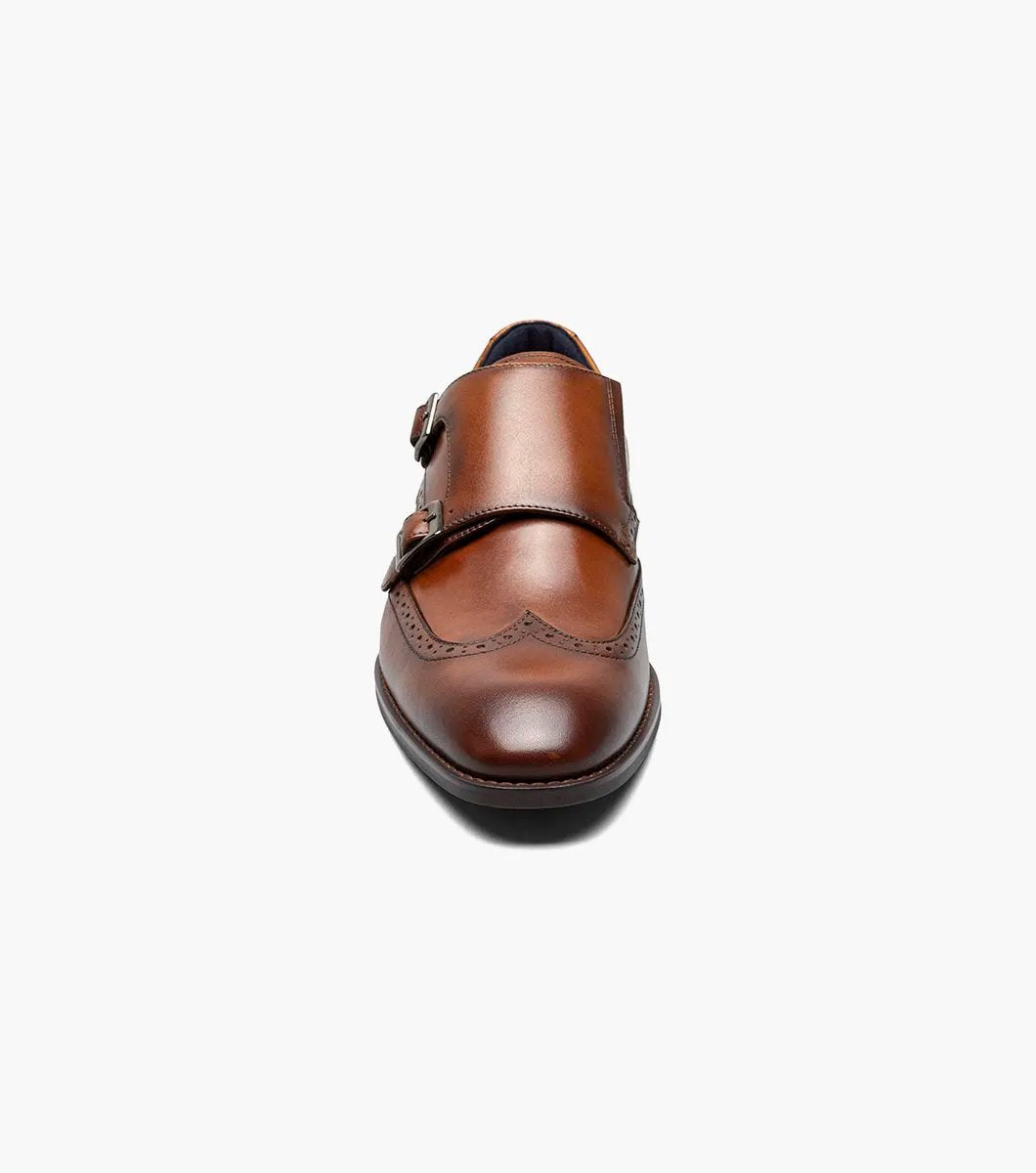 The Stacy Adams - KARSON Wingtip Double Monk Strap in cognac, model number 25570-221, is a shoe crafted with brown leather and features wingtip decorative perforations along with two side buckles, complemented by a RedZone footbed for exceptional comfort.