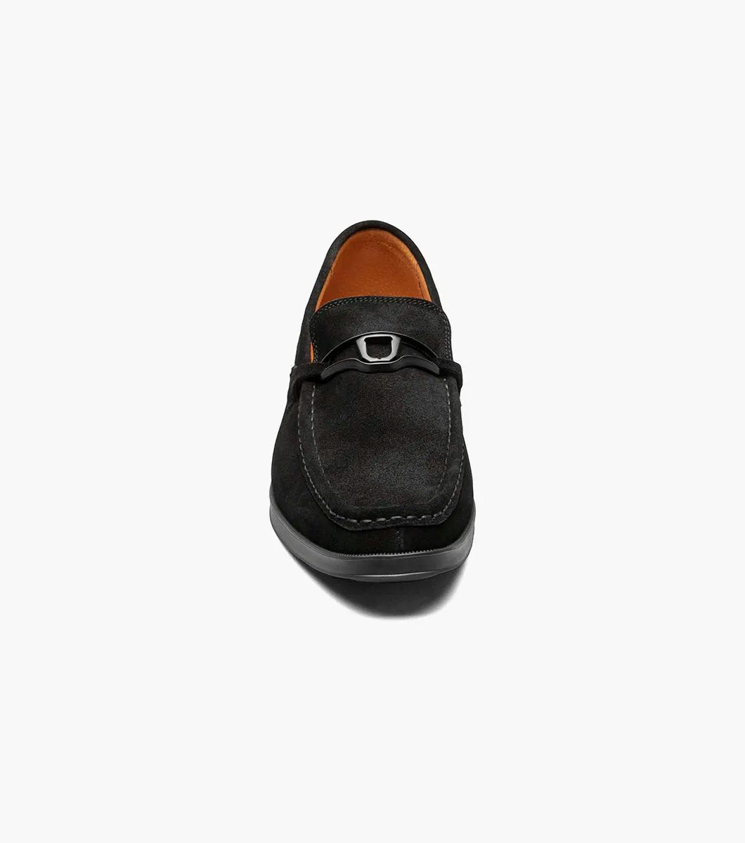 Introducing the Stacy Adams - PALLADIAN Moc Toe Slip On in black suede, featuring a moc toe and metal buckle detail. This stylish shoe includes a cushioned insole, low heel, and visible stitching all presented on a sleek white background.