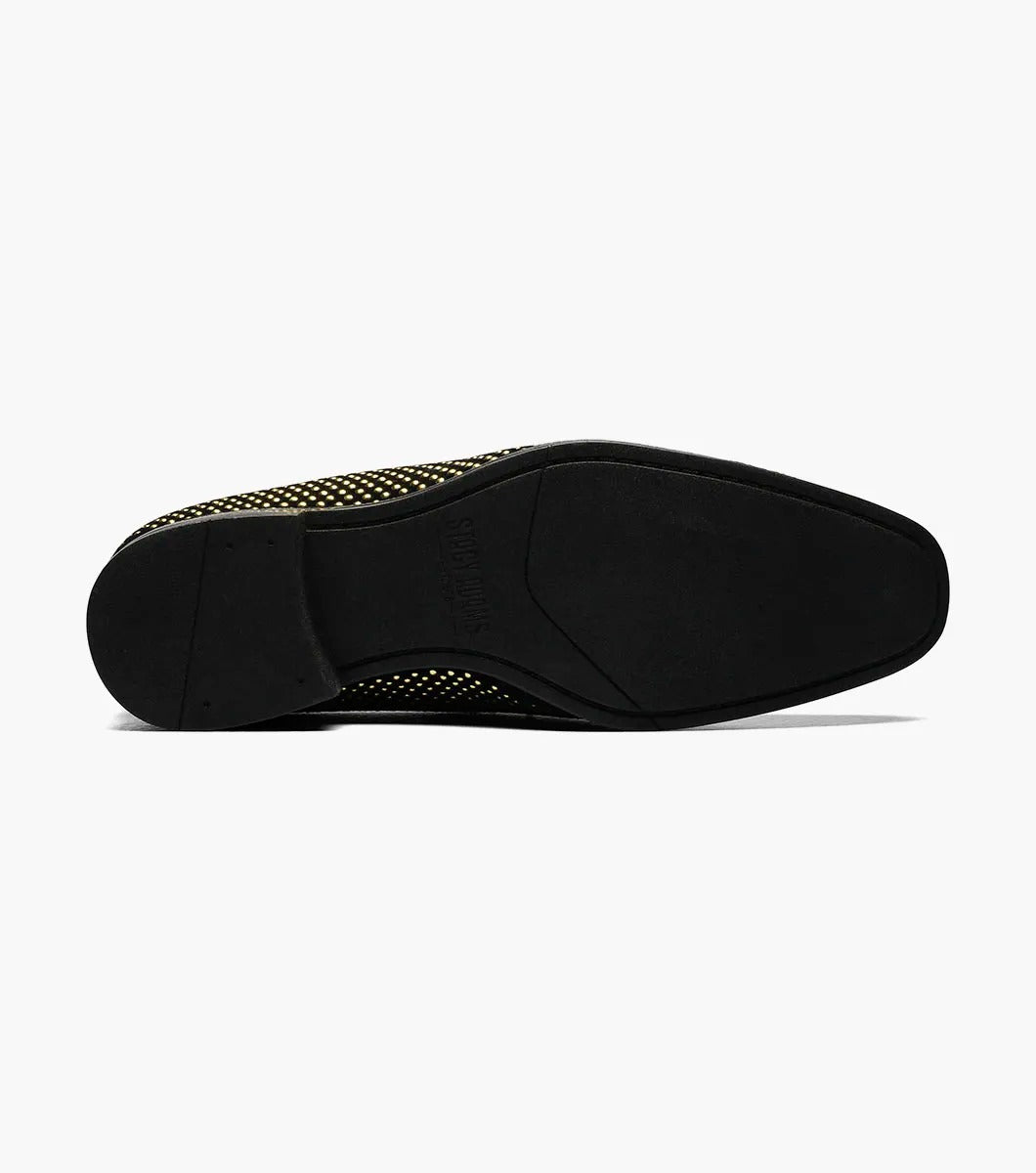 The Stacy Adams - SWAGGER Studded Slip On - Black and Gold - 25228-715 is a black loafer adorned with gold studs and a decorative emblem on top, featuring a comfortable memory foam insole.