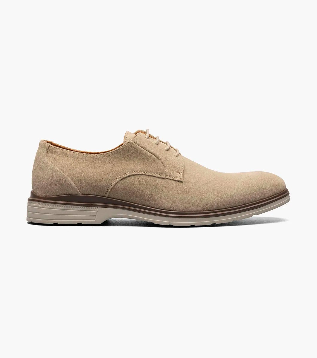 The Stacy Adams TAYSON Plain Toe Lace Up in sandstone is an Oxford shoe made from tan suede. It features anatomical arch support and laces, complemented by a light brown sole. The shoe is displayed against a plain white background.