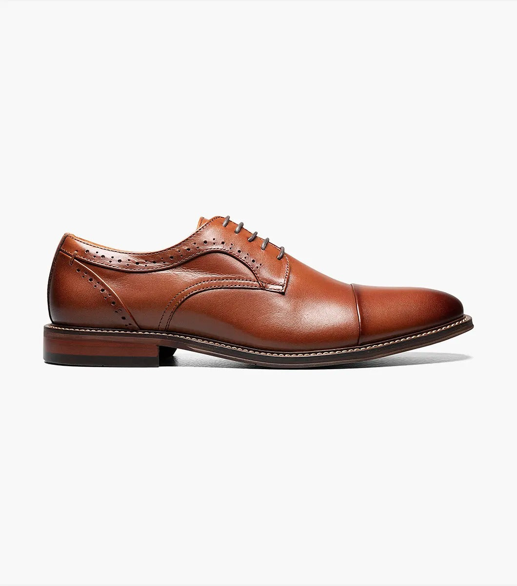 The Stacy Adams MADDOX Cap Toe Oxford in Cognac boasts a burnished leather finish, enhanced with a stylish cap toe and decorative perforations on the sides.