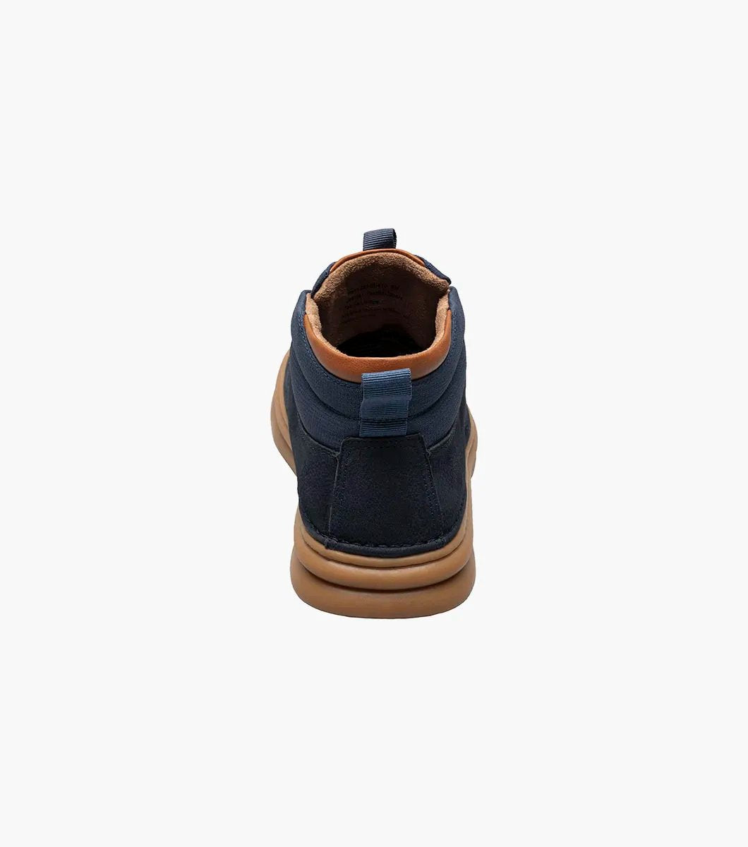 The Stacy Adams DELSON Plain Toe Chukka Boot in Navy showcases a leather upper paired with brown soles and laces, featuring anatomical arch support, set against a white background.