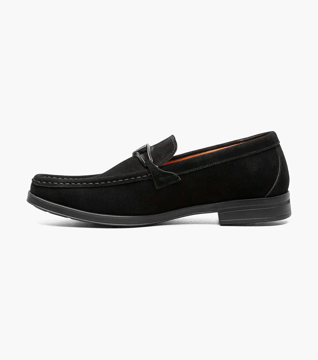 Introducing the Stacy Adams - PALLADIAN Moc Toe Slip On in black suede, featuring a moc toe and metal buckle detail. This stylish shoe includes a cushioned insole, low heel, and visible stitching all presented on a sleek white background.