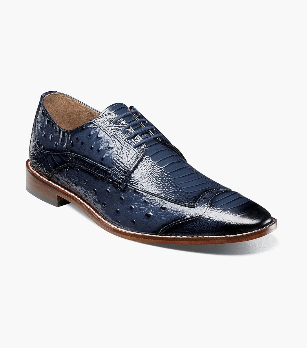 The Stacy Adams FANELLI Modified Wingtip Oxford in blue, product number 25536-400, is an elegant dress shoe made from luxurious ostrich leather. It features a textured pattern and a brown sole, shown here from an angled view.