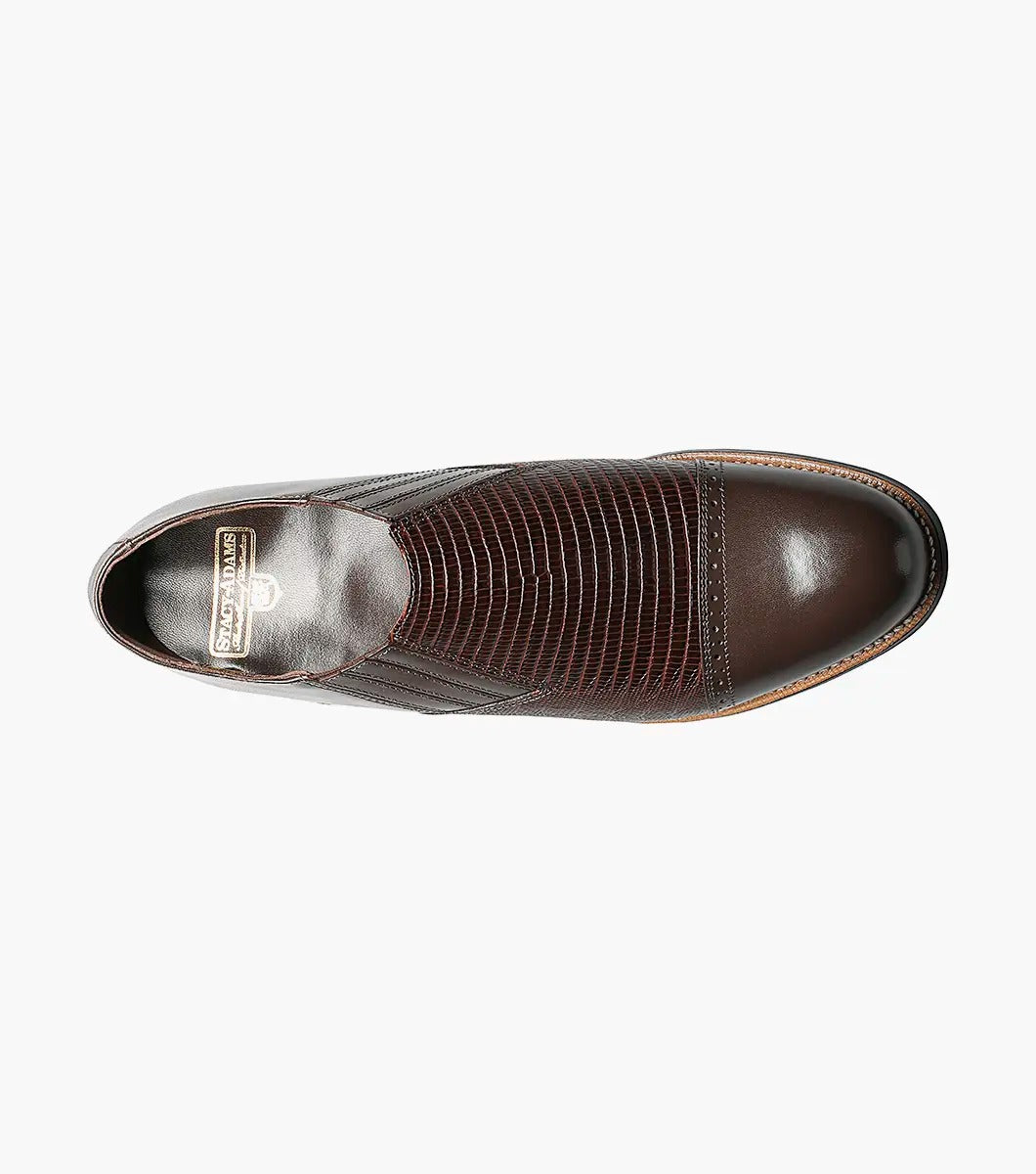 The Stacy Adams - MADISON Cap Toe Slip On in brown is shown in a side profile view against a white background. This shoe features embossed detailing and a low heel, crafted with Goodyear welt construction.