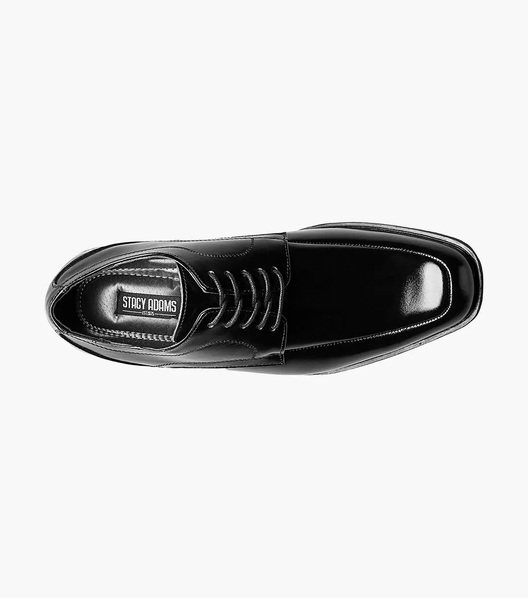 The Stacy Adams Calhoun Moc Toe Oxford, Model 20117-001, is a genuine leather dress shoe in polished black. This STACY ADAMS shoe features laces, a low heel, and boasts a sleek design. It is elegantly displayed against a white background.