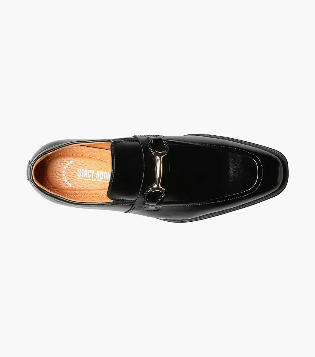 The Stacy Adams PIERCE Moc Toe Bit Slip On in black, style number 25245-001, features a metallic buckle detail and a low heel. It comes with a comfortable Memory Foam insole and is displayed against a white background.