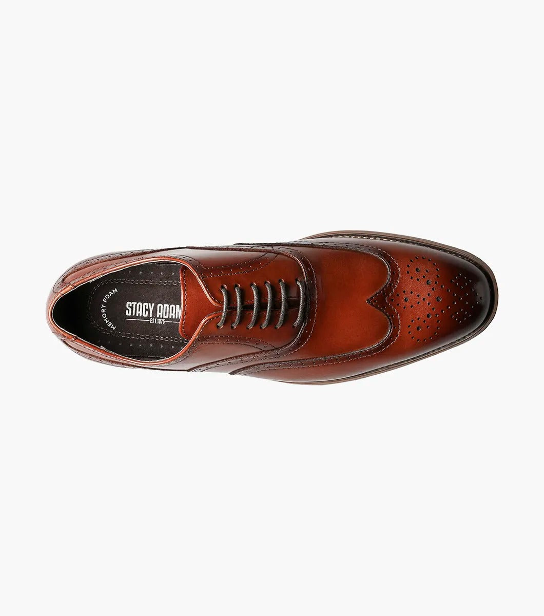 The Stacy Adams DUNBAR Wingtip Oxford shoe, model number 25064-221 in Cognac, showcases a leather upper with intricate stitching and perforations. This elegant design is completed with a low wooden heel, creating timeless sophistication against a white background.