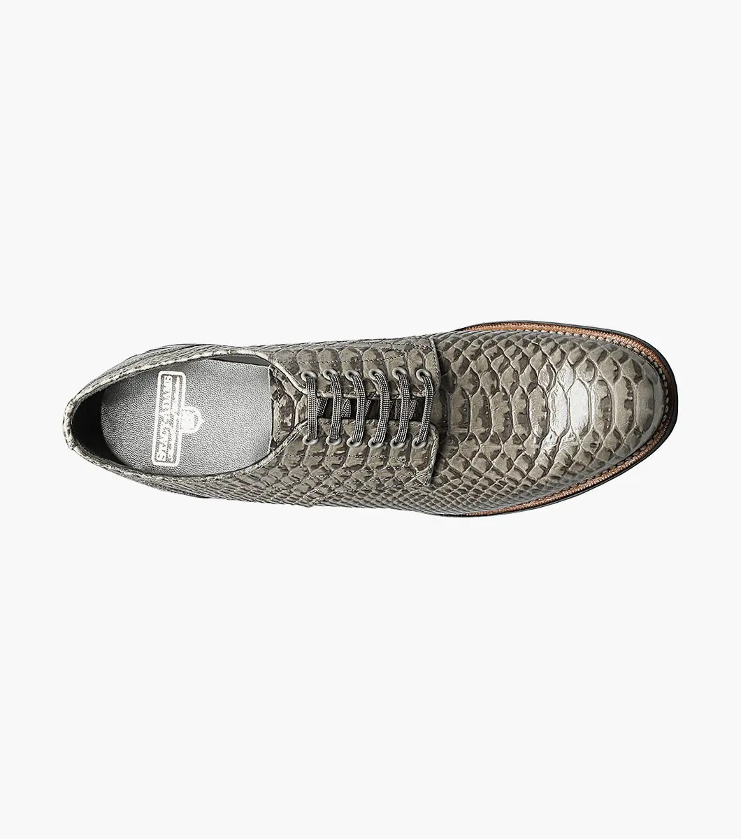 The Stacy Adams Madison Anaconda Plain Toe Oxford in gray showcases a sleek snakeskin pattern, complemented by a black leather outsole and matching laces, all elegantly displayed on a white background.