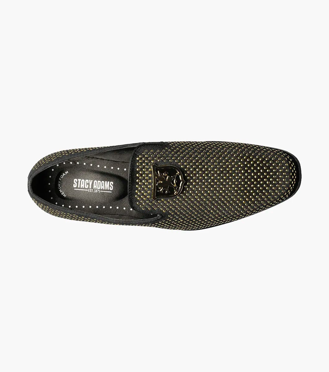 The Stacy Adams - SWAGGER Studded Slip On - Black and Gold - 25228-715 is a black loafer adorned with gold studs and a decorative emblem on top, featuring a comfortable memory foam insole.