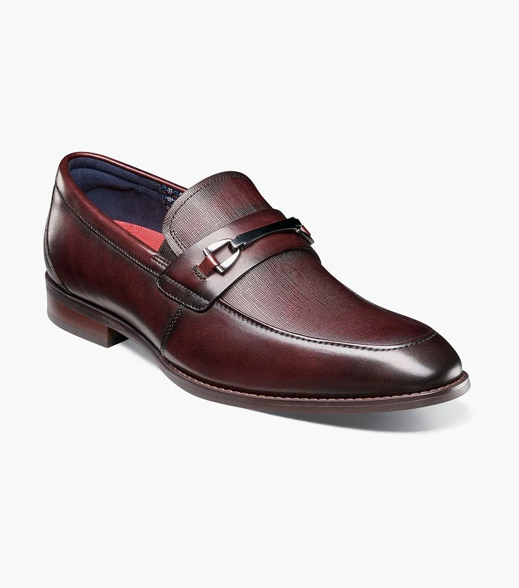 The Stacy Adams KAYLOR Moc Toe Bit Slip On in Burgundy, product number 25572-601, features a metal buckle detail, leather upper, low heel, and dark sole set against a plain white background.