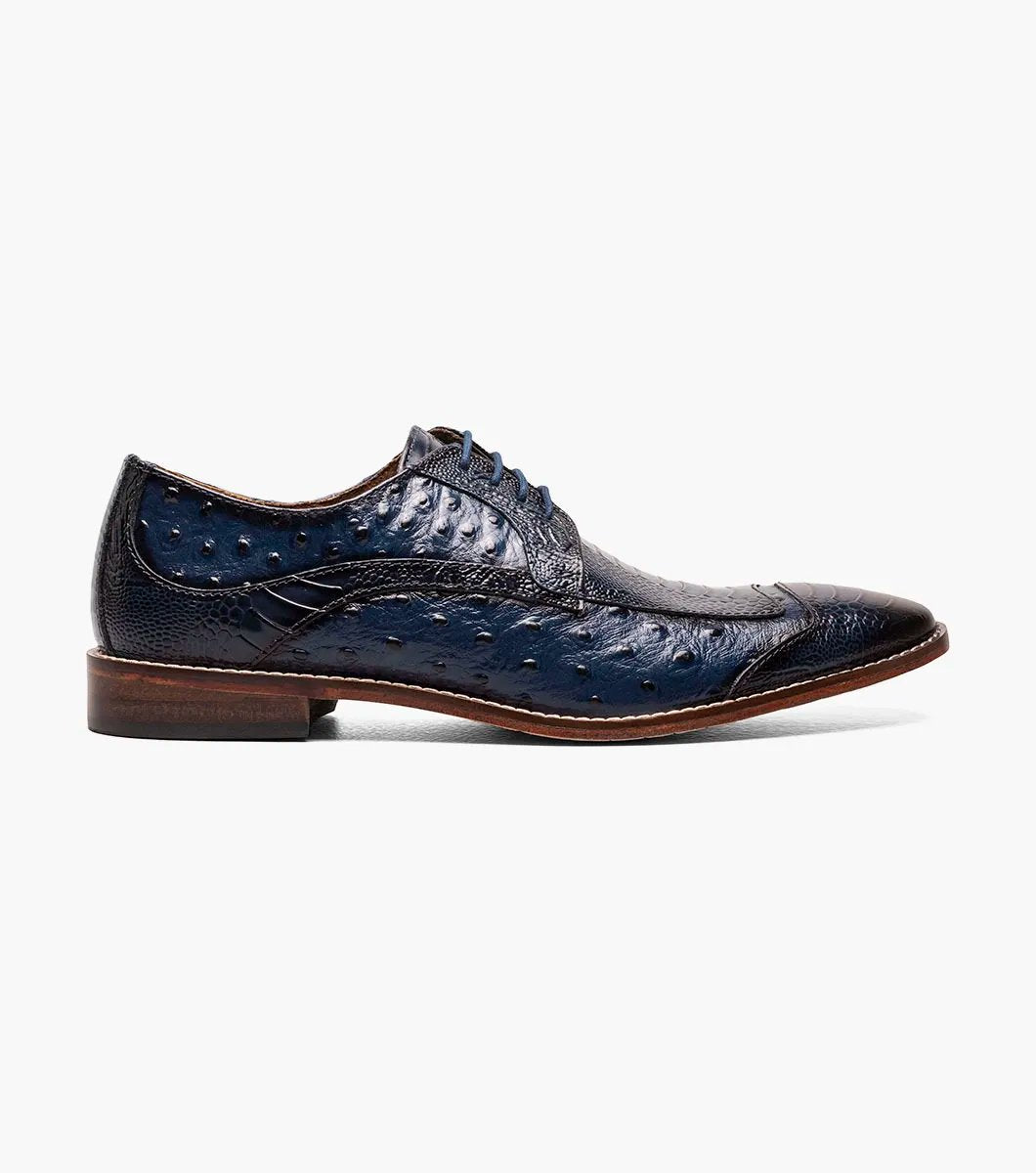 The Stacy Adams FANELLI Modified Wingtip Oxford in blue, product number 25536-400, is an elegant dress shoe made from luxurious ostrich leather. It features a textured pattern and a brown sole, shown here from an angled view.