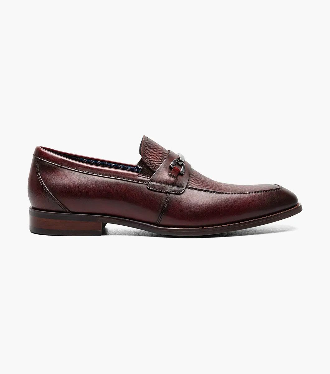 The Stacy Adams KAYLOR Moc Toe Bit Slip On in Burgundy, product number 25572-601, features a metal buckle detail, leather upper, low heel, and dark sole set against a plain white background.