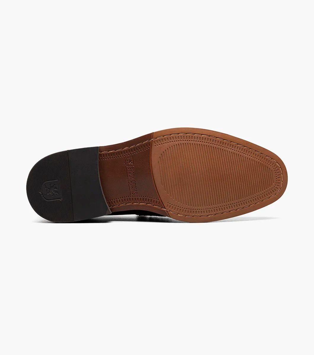 The Stacy Adams MARLOWE Algonquin Moc Toe Penny Slip On in Cognac showcases a sophisticated brown leather design with a low heel and intricate stitching details, equipped with a RedZone Footbed for enhanced comfort.