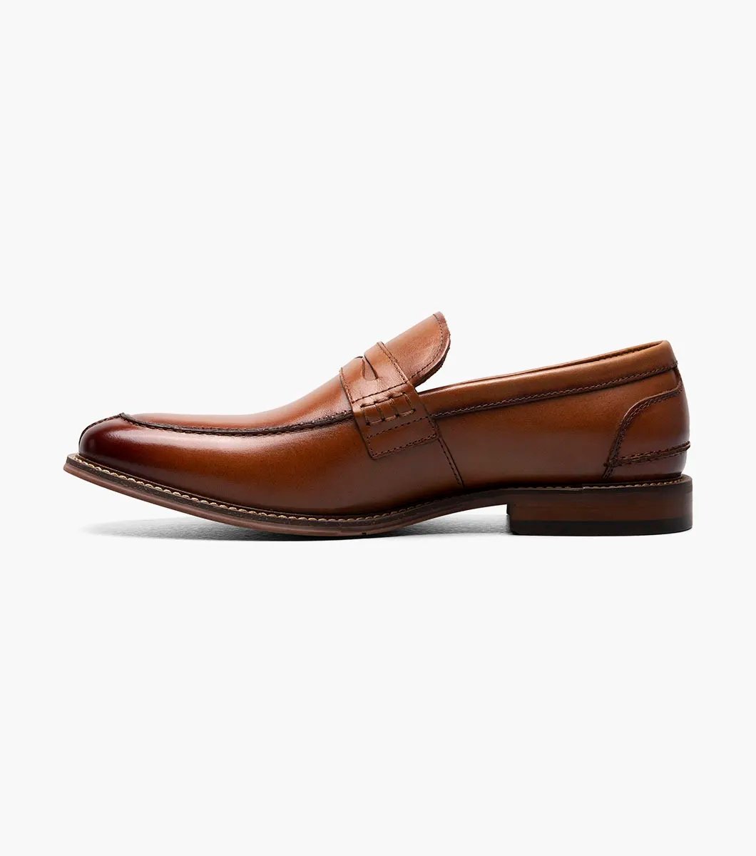 The Stacy Adams - MARLOWE Algonquin Moc Toe Penny Slip On in Cognac, with a leather upper and detailed stitching on a low heel, is showcased against a white background.