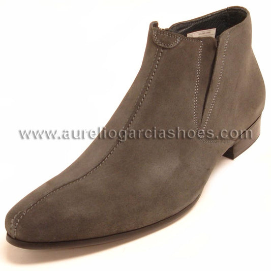 The FI-3101-S Grey Suede Encore By Fiesso fashion boot from Fiesso showcases a gray suede ankle design with a low heel and noticeable stitching along the seams, accented by an embossed sleek website URL on its leather upper for an additional touch of sophistication.