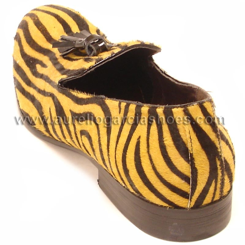 The FI-6773 Black Gold Fiesso By Aurelio Garcia shoes offer a brown and yellow zebra print loafer design, made from pony hair leather. They feature a tassel detail on the upper and come with a cushioned insole for enhanced comfort.