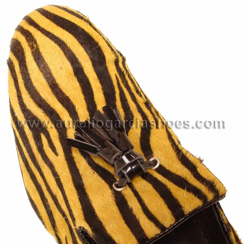 The FI-6773 Black Gold Fiesso By Aurelio Garcia shoes offer a brown and yellow zebra print loafer design, made from pony hair leather. They feature a tassel detail on the upper and come with a cushioned insole for enhanced comfort.