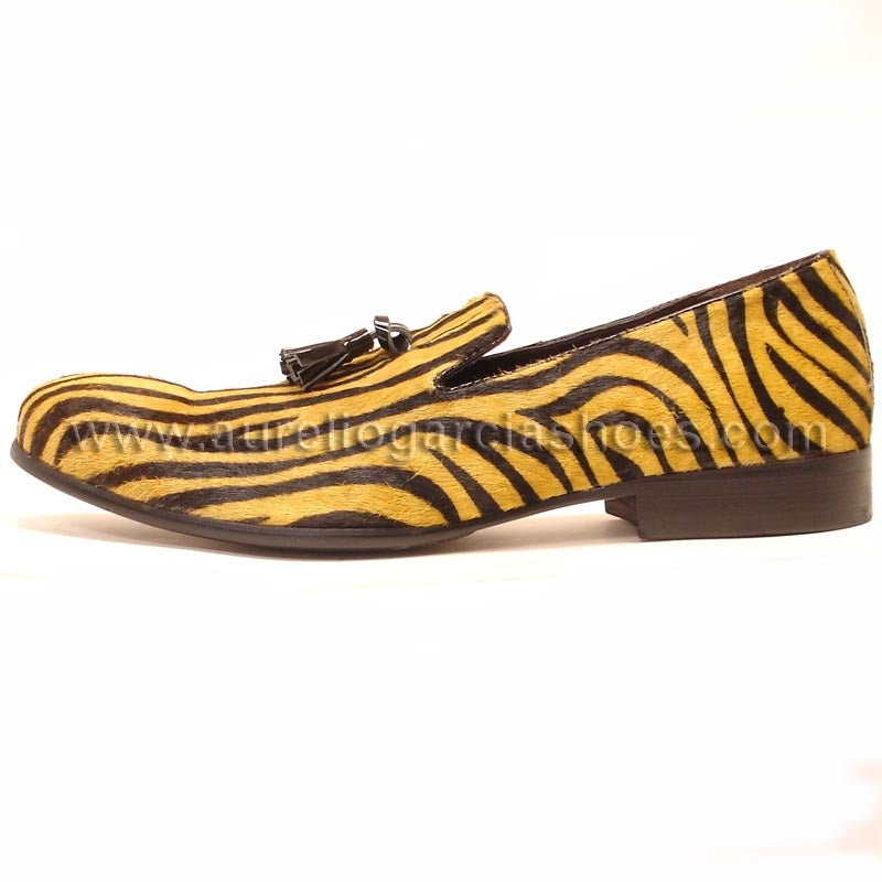 The FI-6773 Black Gold Fiesso By Aurelio Garcia shoes offer a brown and yellow zebra print loafer design, made from pony hair leather. They feature a tassel detail on the upper and come with a cushioned insole for enhanced comfort.