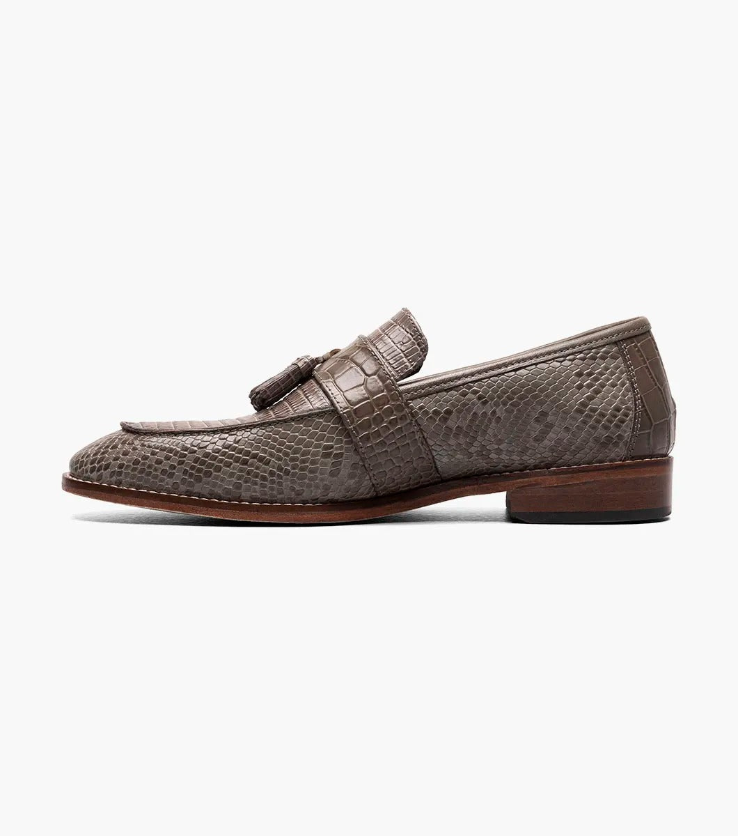 Gray tassel loafer designed by Stacy Adams, made from lizard print leather with dark brown trim and a low heel. It includes a Memory Foam insole for enhanced comfort and is displayed against a plain background.