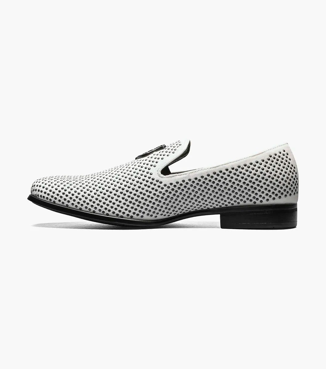 The Stacy Adams - SWAGGER Studded Slip On (Black with White, 25228-111) showcases a striking design with a white studded leather loafer contrasted by a black sole and adorned with a decorative metal emblem on top, offering both style and comfort thanks to its Memory Foam insole.