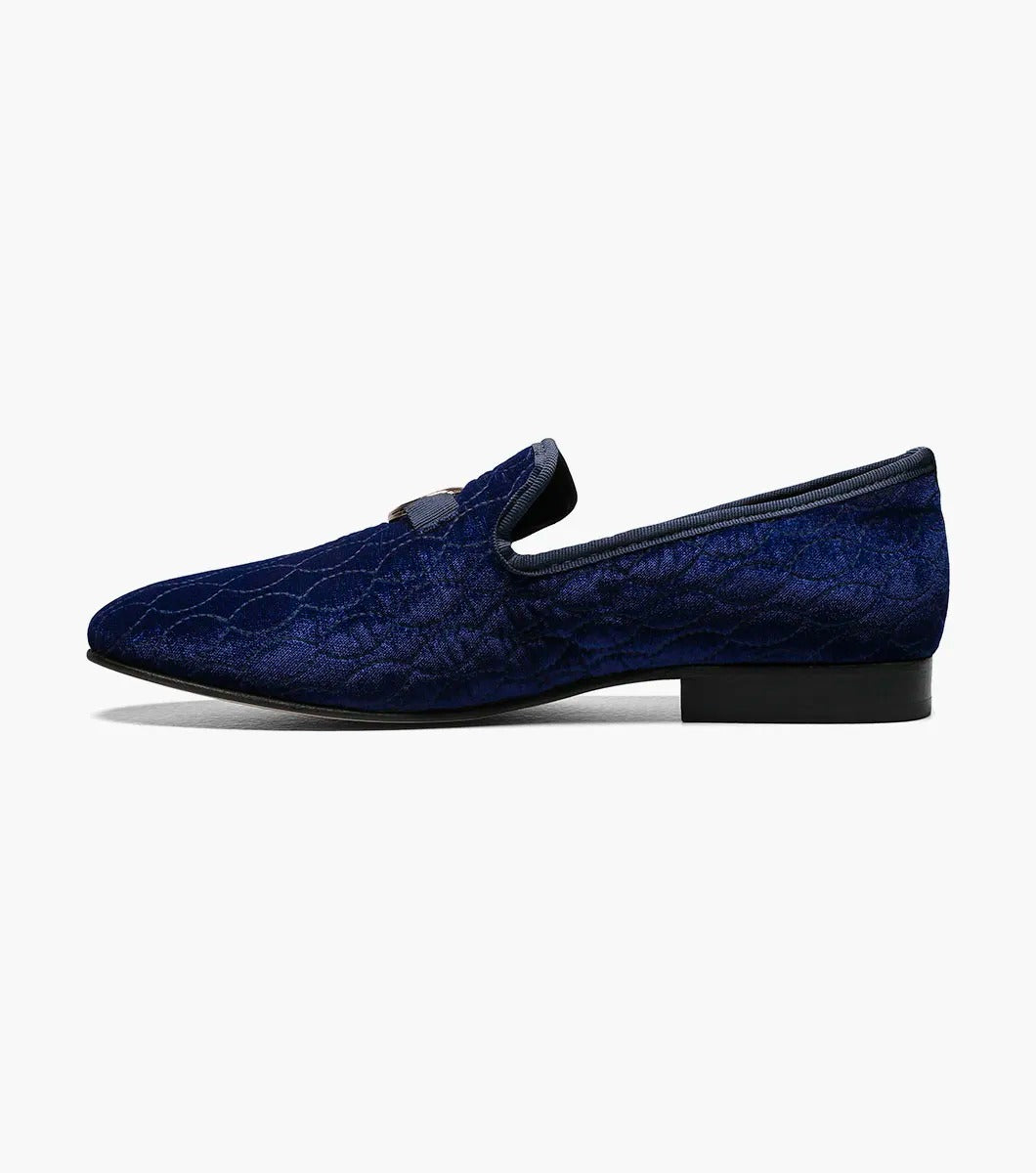 The Stacy Adams VALET Slip On Bit Loafer, model 25166-400, combines quilted velour in a striking blue with a sleek black sole and is elegantly decorated with a gold emblem on top. It also features a Memory Foam insole for enhanced comfort.