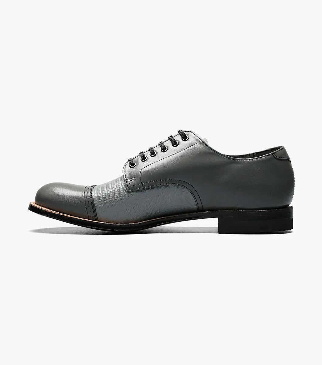 The Stacy Adams Madison Lizard Cap Toe Oxford in Steel Gray showcases a unique lizard print design and textured cap toe, complemented by black laces.