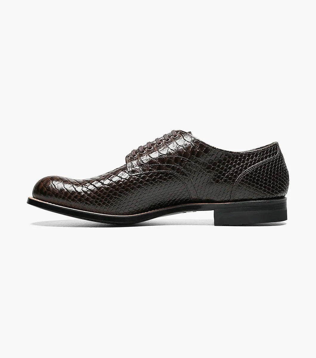 The Stacy Adams MADISON Anaconda Plain Toe Oxford in brown showcases an anaconda print with black laces, set against a white background.