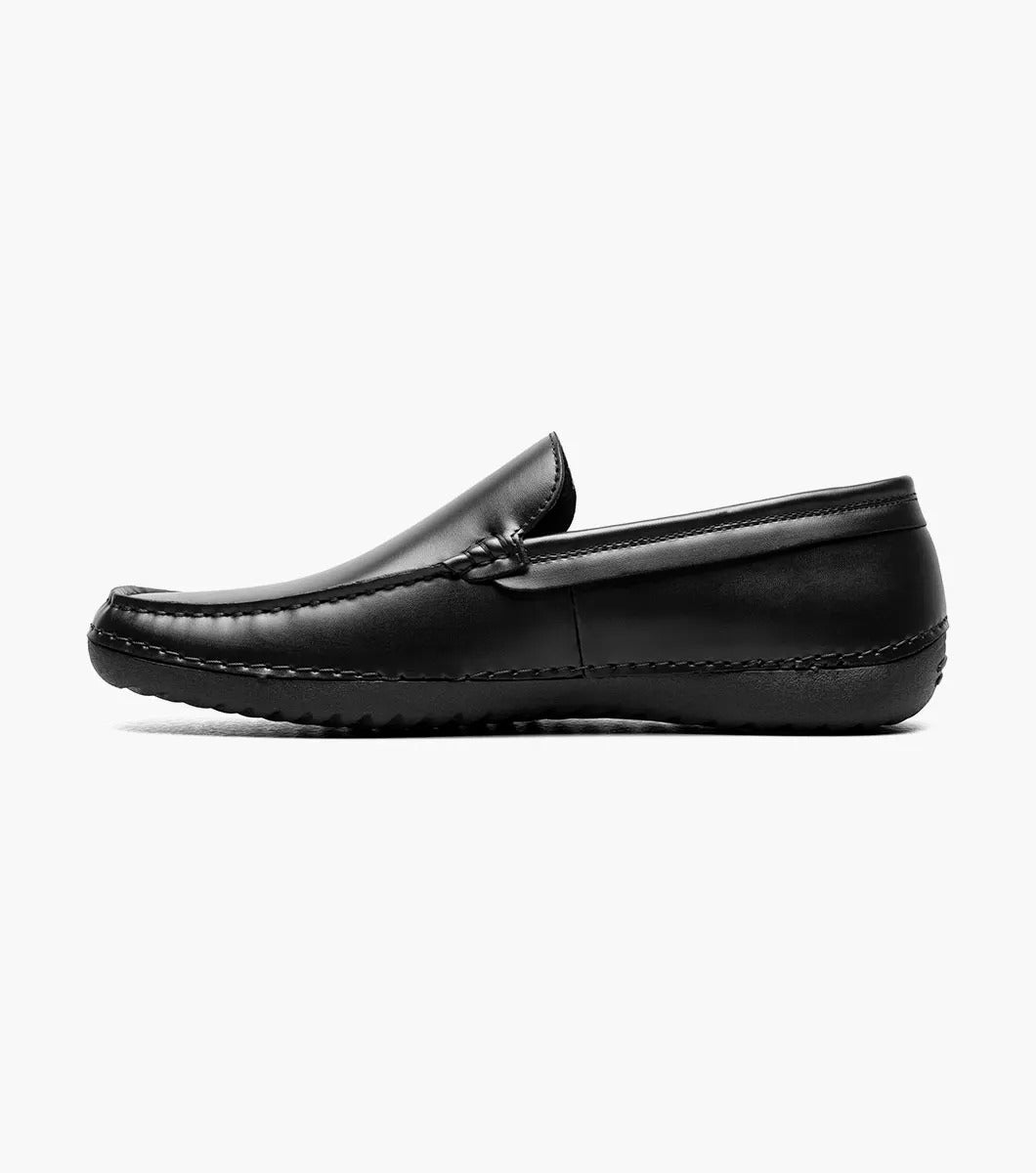 A Stacy Adams DEL Moc Toe Loafer in black leather, featuring a discreet logo on the side. The interior is lined with a striped pattern, providing both style and comfort.