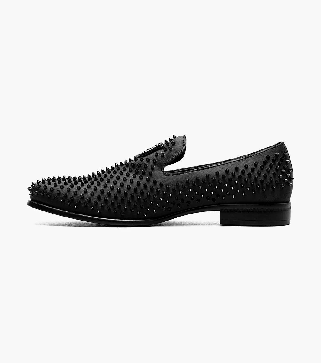 The Stacy Adams SABRE Spiked Slip On (21528-001) boasts a black studded design with a shiny emblem on the upper. Enhanced with Memory Foam, this stylish shoe from STACY ADAMS delivers both flair and comfort, all set against a pristine white background.