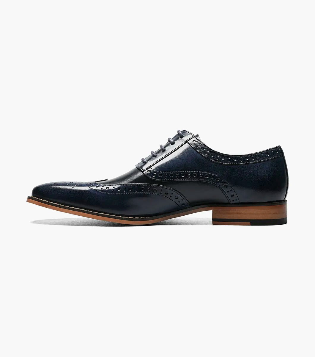 A Stacy Adams TINSLEY Wingtip Oxford in Cobalt Multi, featuring buffalo leather with decorative perforations, memory foam for added comfort, a wooden heel, and laces.