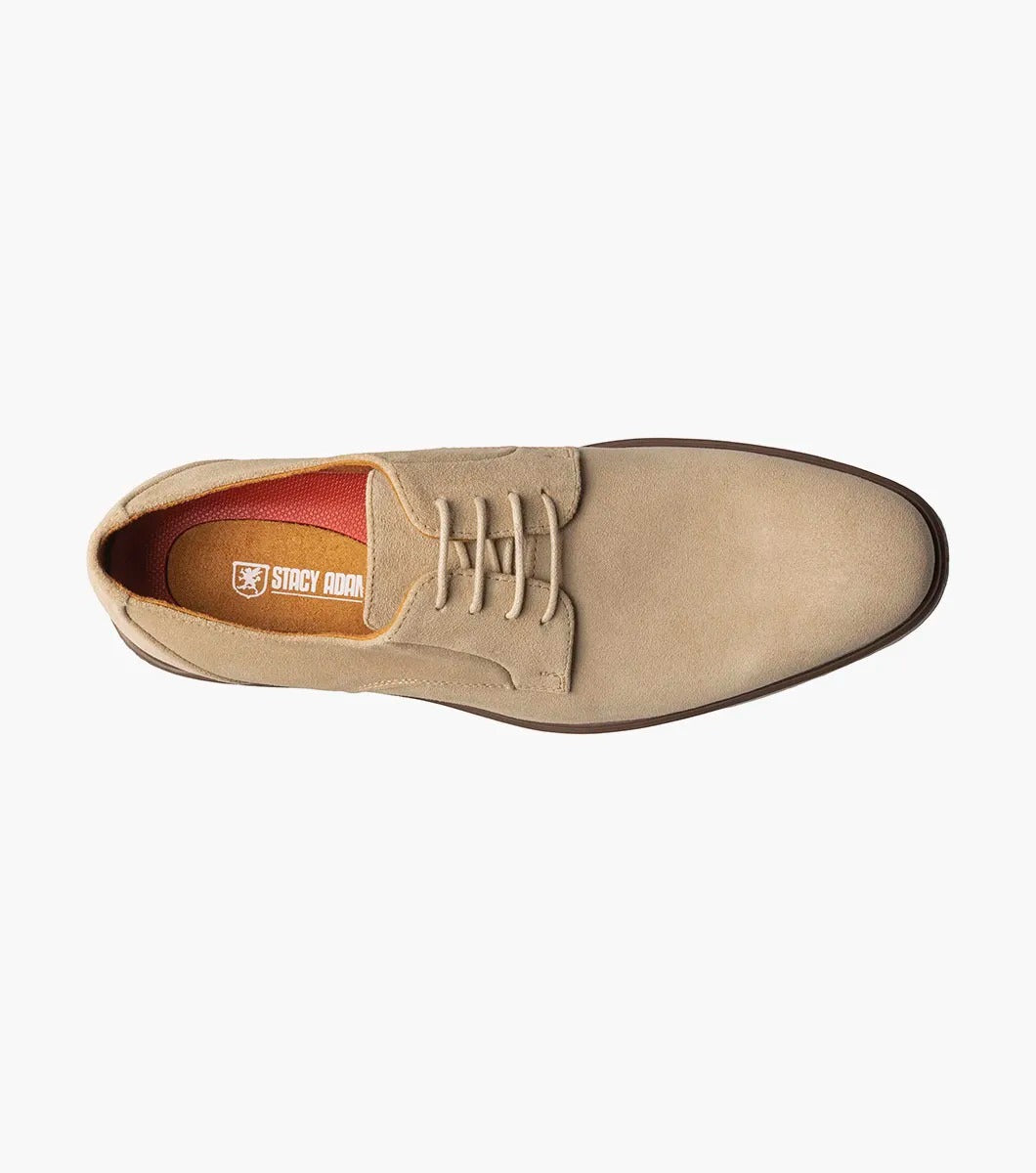 The Stacy Adams TAYSON Plain Toe Lace Up in sandstone is an Oxford shoe made from tan suede. It features anatomical arch support and laces, complemented by a light brown sole. The shoe is displayed against a plain white background.