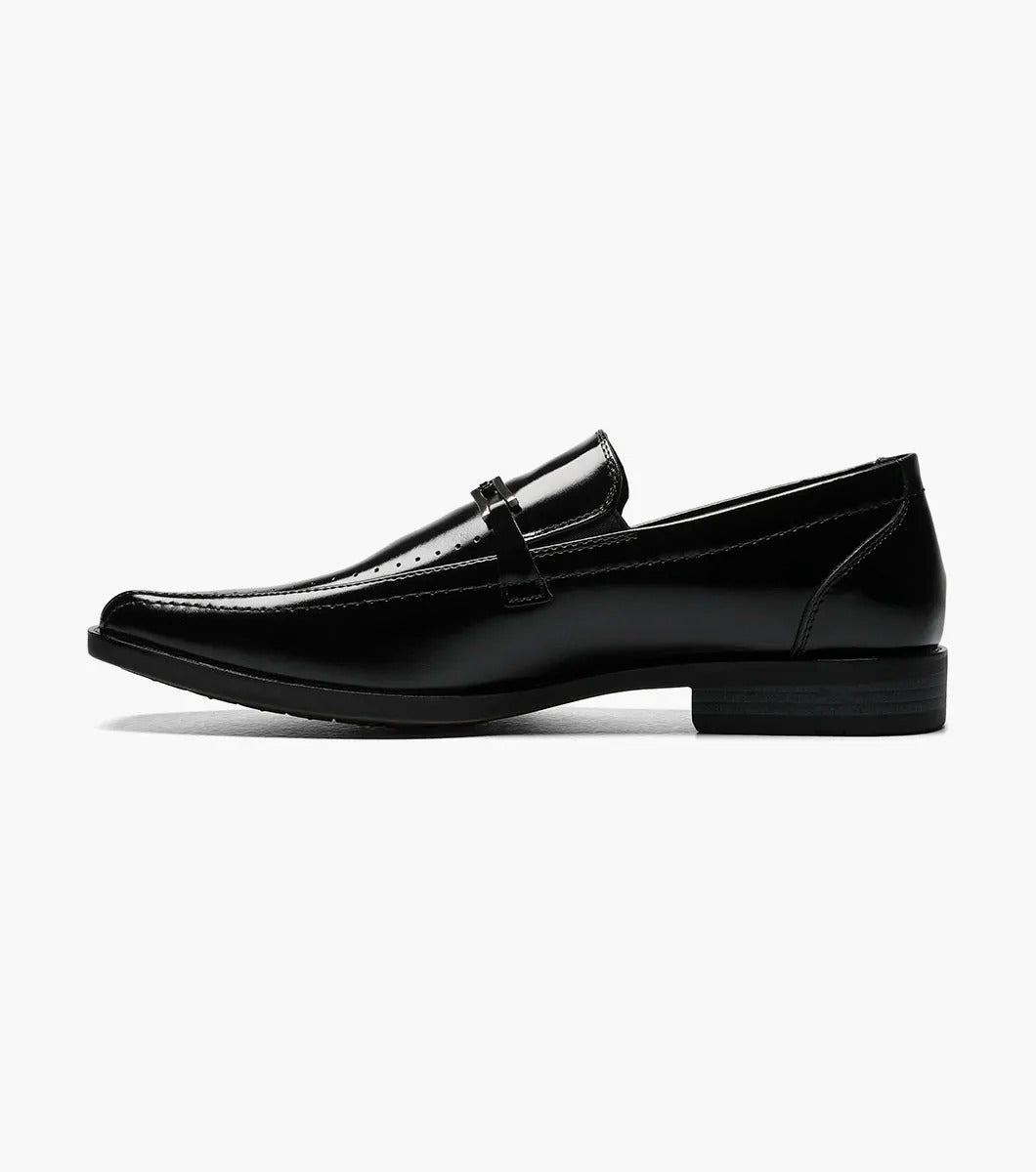 The Stacy Adams CADE Bike Toe Slip On in black, model 20126-001, is a stylish black leather loafer with a slip-on design. It features a gunmetal bit and a low heel, set against a plain white background.