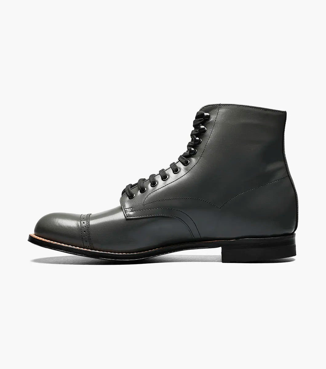 The Stacy Adams MADISON Cap Toe Boot in Steel Gray, made from high-quality kidskin leather, showcases a sophisticated lace-up design and a polished cap toe, enhanced by a sturdy black sole set against a crisp white backdrop.