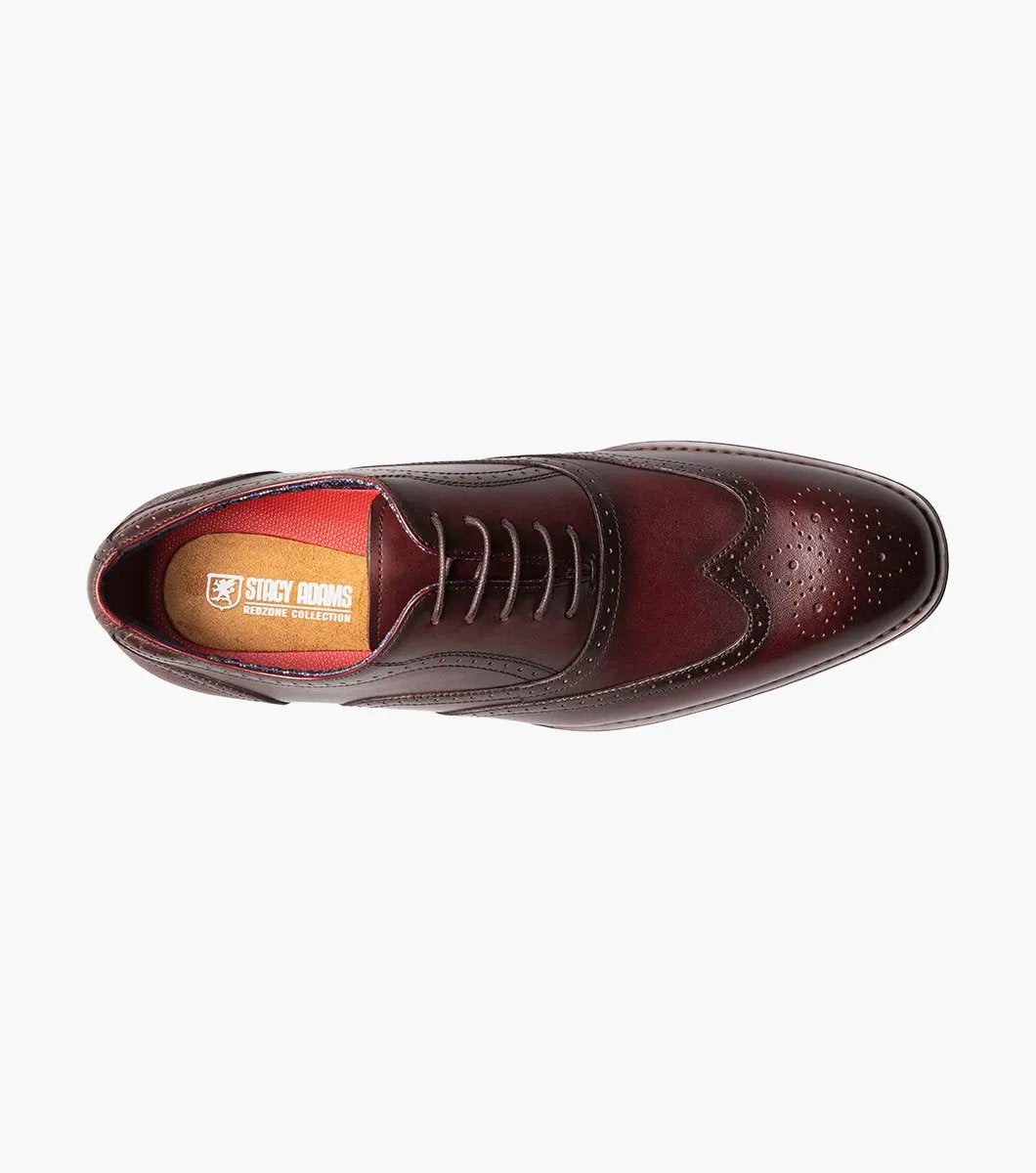 The Stacy Adams KAINE Wingtip Oxford in Burgundy, model number 25569-601, showcases a leather upper with decorative perforations and a classic wingtip design. This brogue dress shoe features a low heel and is photographed on a white background, highlighting its elegance and anatomical arch support for added comfort.