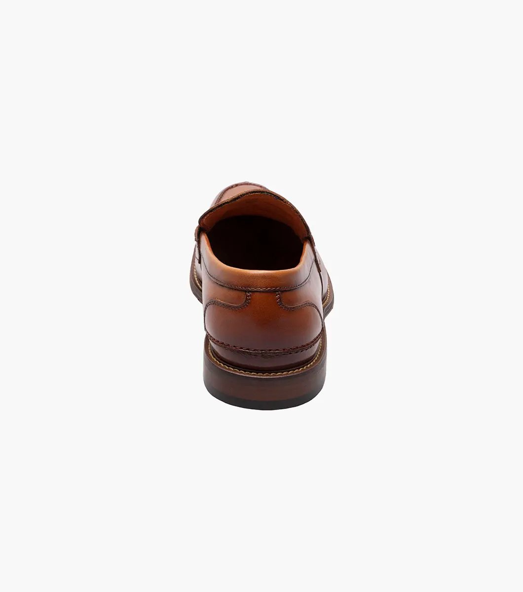 The Stacy Adams - MARLOWE Algonquin Moc Toe Penny Slip On in Cognac, with a leather upper and detailed stitching on a low heel, is showcased against a white background.