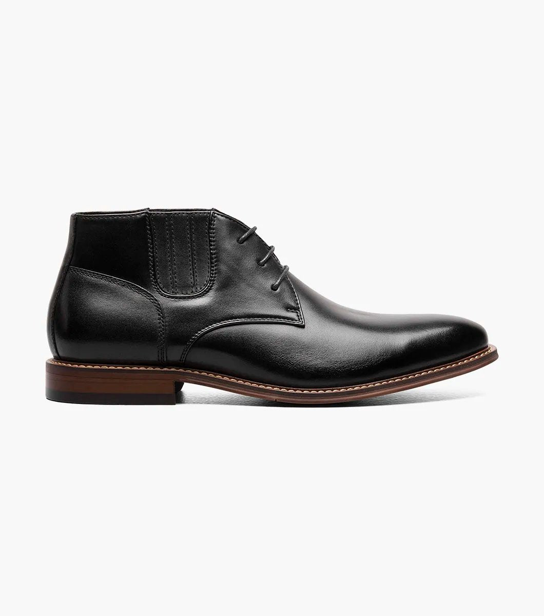 Introducing the Stacy Adams - MAXWELL Plain Toe Chukka Boot in Black, model 25551-001. This versatile boot features a sleek polished finish, a contrasting brown welt, and three pairs of lace eyelets. Set atop a wooden sole, it is designed with anatomical arch support to ensure maximum comfort.