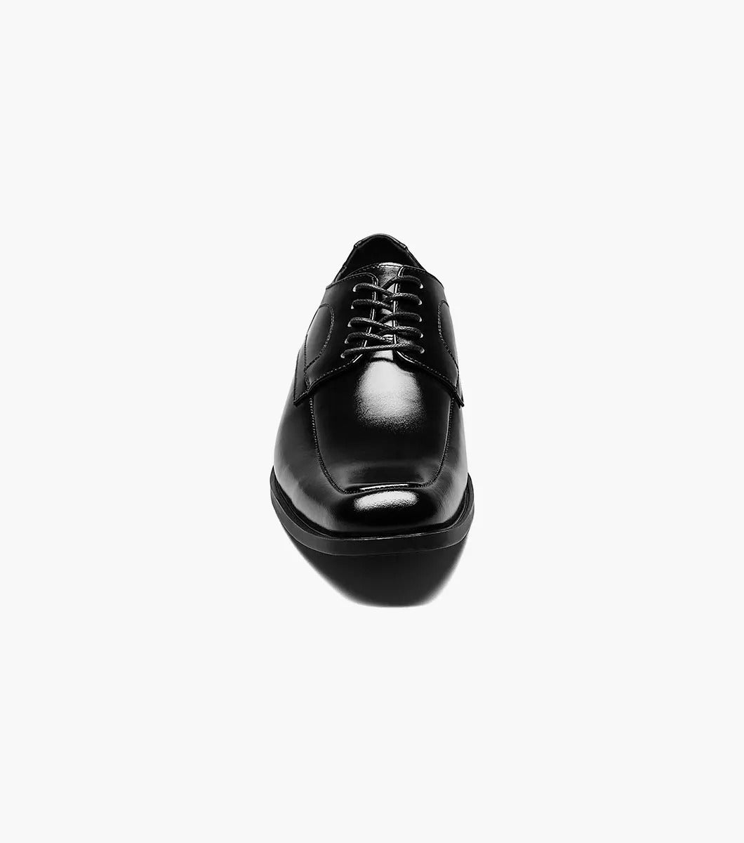 The Stacy Adams Calhoun Moc Toe Oxford, Model 20117-001, is a genuine leather dress shoe in polished black. This STACY ADAMS shoe features laces, a low heel, and boasts a sleek design. It is elegantly displayed against a white background.