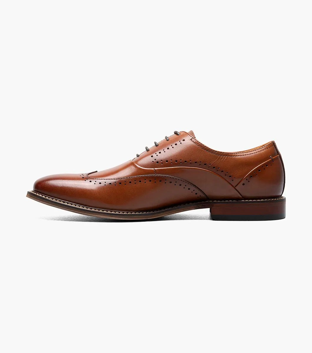 The Stacy Adams - MACARTHUR Wingtip Oxford in Cognac (25489-221) showcases a polished leather design with detailed brogue accents against a white background.