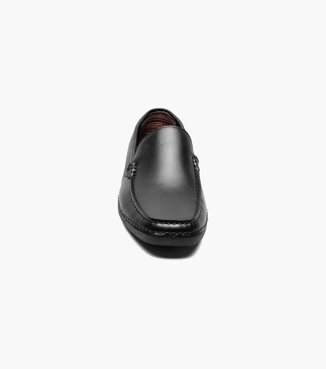 A Stacy Adams DEL Moc Toe Loafer in black leather, featuring a discreet logo on the side. The interior is lined with a striped pattern, providing both style and comfort.