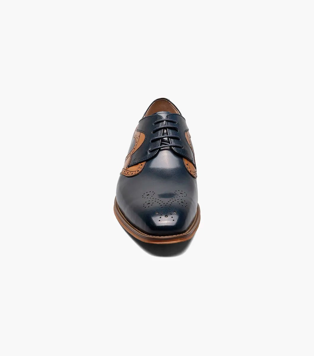 A side view of the Stacy Adams - PALMER Plain Toe Medallion Oxford showcases its navy and brown leather design, complete with decorative perforations and a wooden heel.