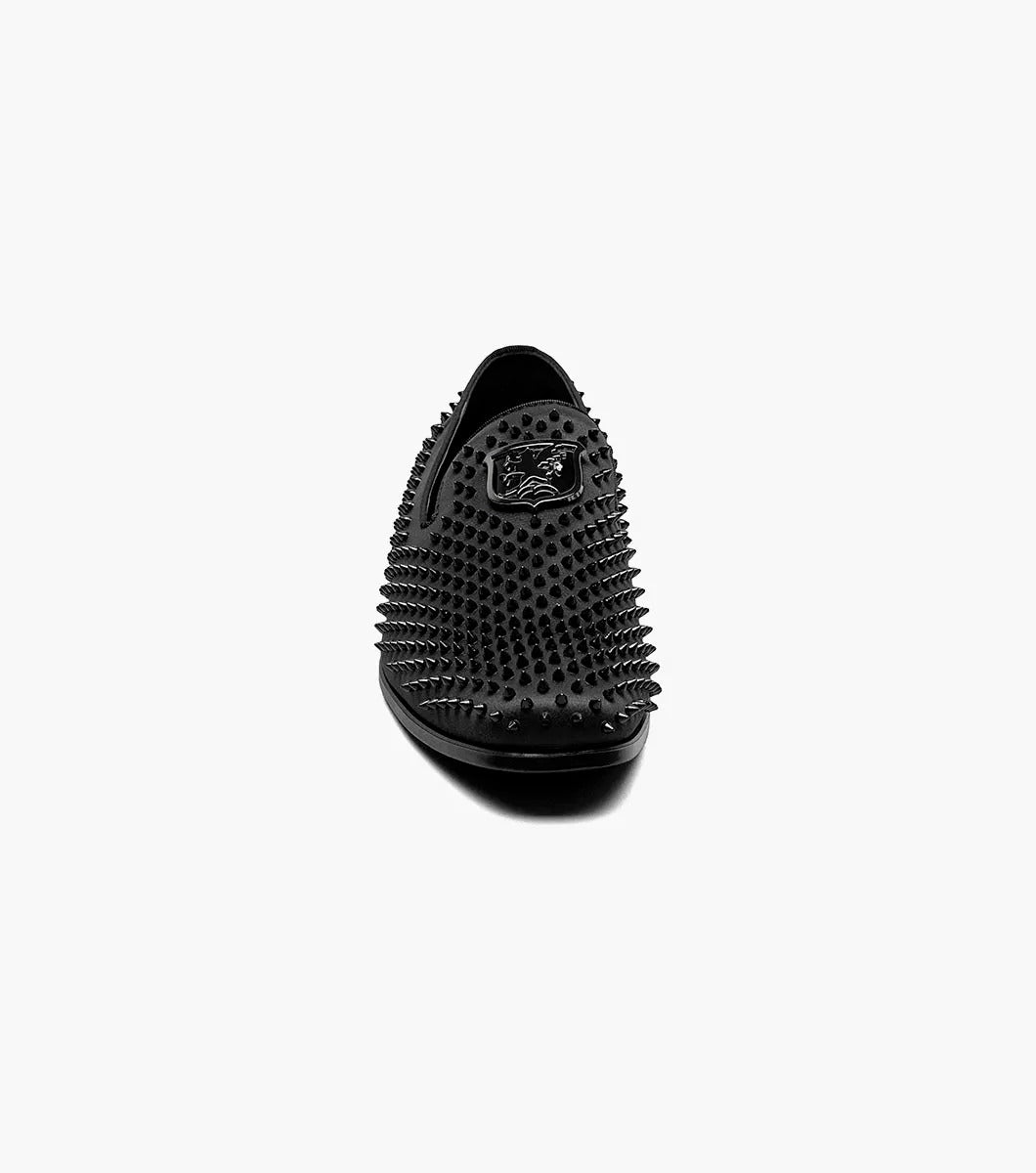 The Stacy Adams SABRE Spiked Slip On (21528-001) boasts a black studded design with a shiny emblem on the upper. Enhanced with Memory Foam, this stylish shoe from STACY ADAMS delivers both flair and comfort, all set against a pristine white background.