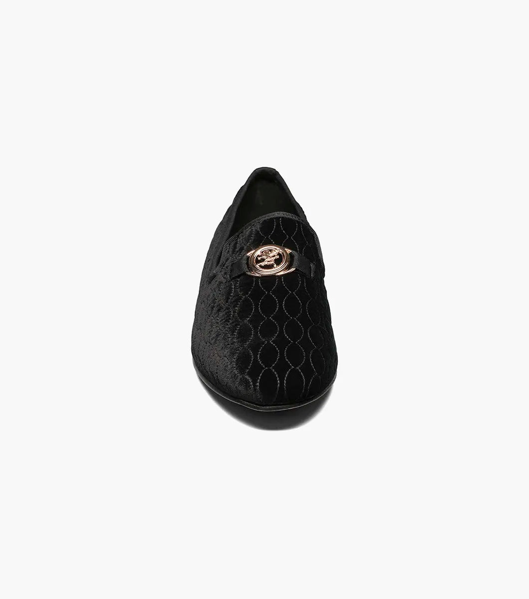 The Stacy Adams VALET Slip On Bit Loafer in Black (25166-001) showcases a black velvet design with a quilted pattern and gold emblem on top, enhanced by a genuine leather sole and cushioned with a Memory Foam insole for superior comfort.