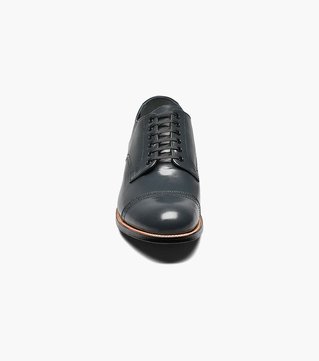 A refined Stacy Adams MADISON Cap Toe Oxford in navy, crafted from luxurious kidskin leather with elegant laces, features a polished cap toe design and a low heel against a white background.