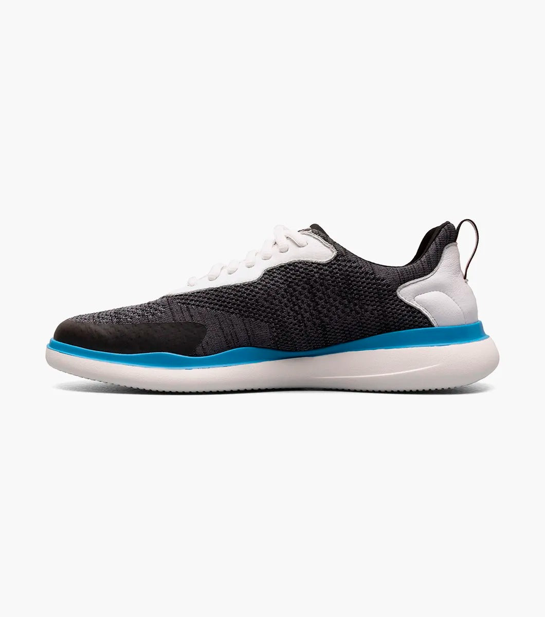 The Stacy Adams - MAXSON Moc Toe Lace Up Sneaker in Black Multi presents a stylish design with a white sole and blue accent, complemented by white laces and a textured mixed material upper for durability. This sneaker also provides anatomical arch support to ensure enhanced comfort with every step.