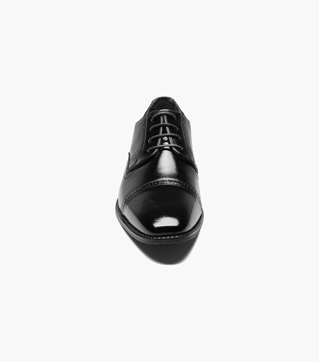 The STACY ADAMS - ABBOTT Cap Toe Oxford in Black (20159-001) is an elegant black dress shoe, made from genuine leather, with a stylish cap toe design, lace-up closure, and a slip-resistant sole, all beautifully showcased against a white background.